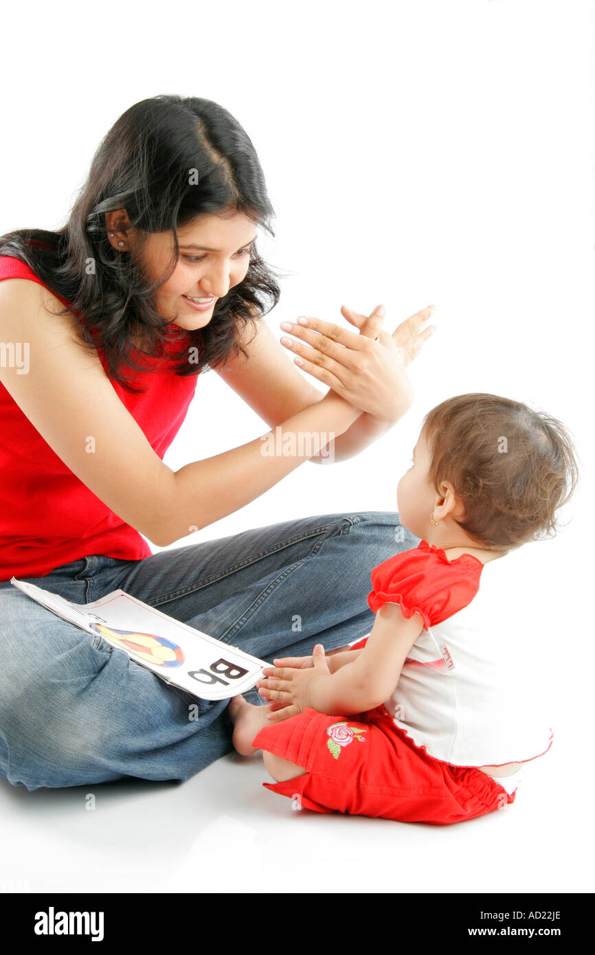 Indian giovane madre in jeans blu e rosso tee shirt insegnando il suo bambino baby B per la farfalla con azione su sfondo bianco - ssk 71683 Foto Stock