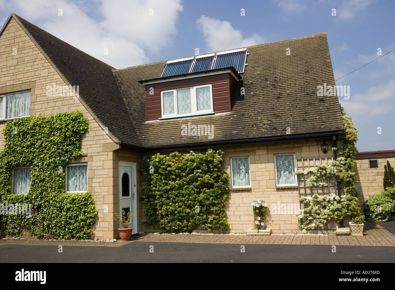 Tre moderni solare termico pannelli con tubi evacuati sul tetto di casa unifamiliare Costwolds REGNO UNITO Foto Stock