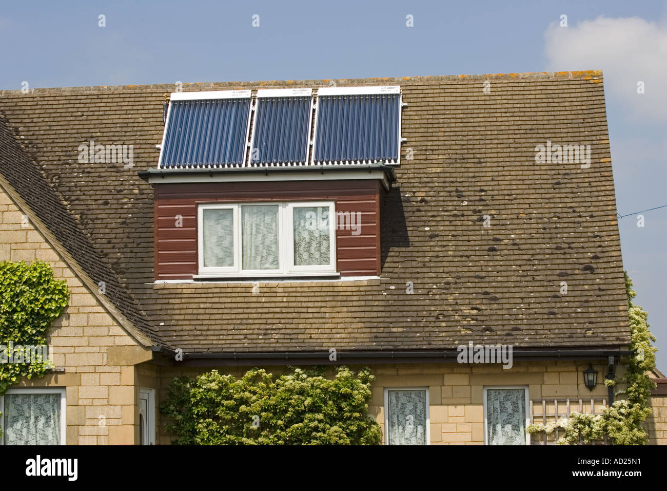 Tre moderni solare termico pannelli con tubi evacuati sul tetto di casa unifamiliare Costwolds REGNO UNITO Foto Stock