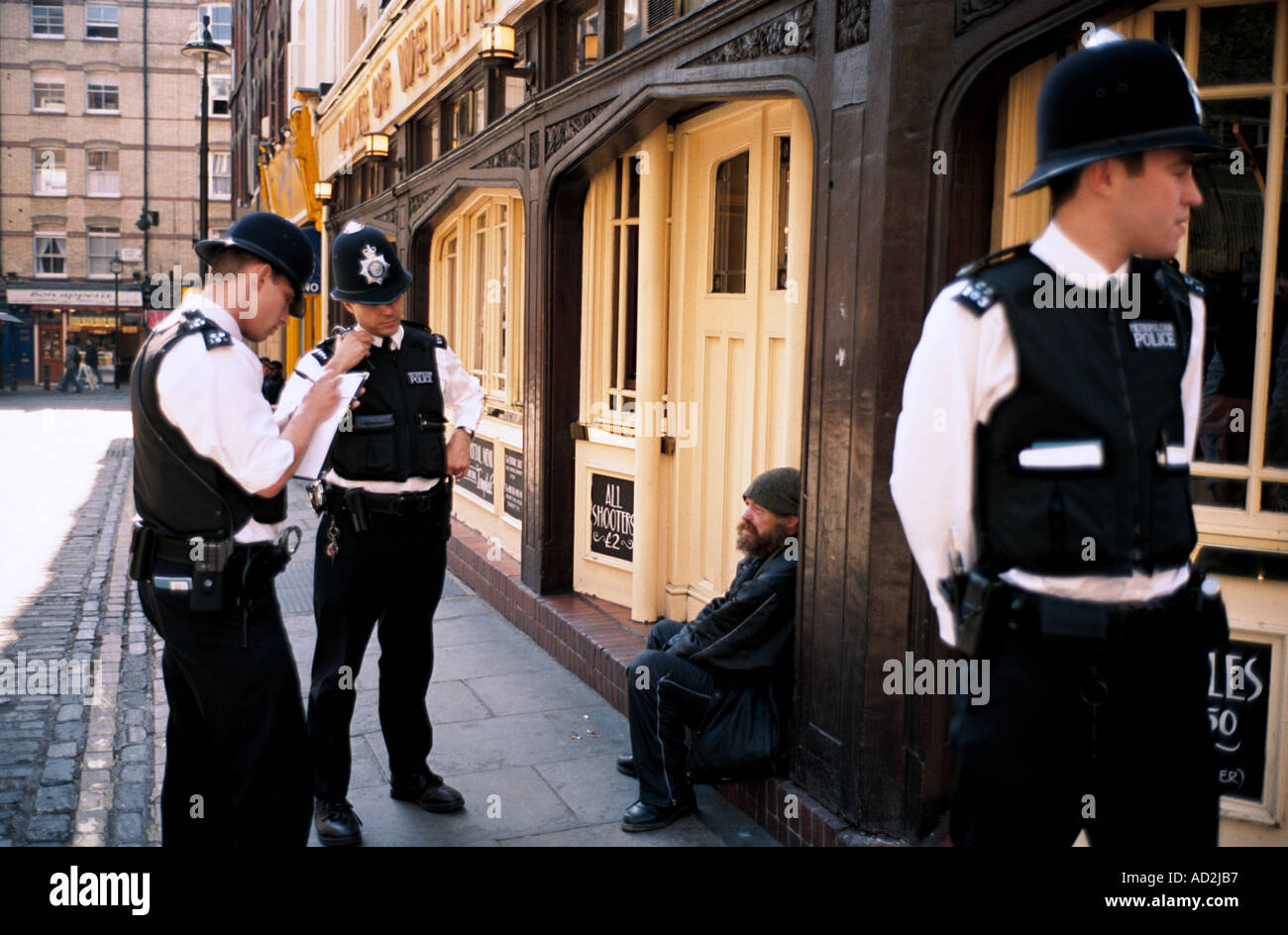 Metropolitan poliziotti controllare l identità di un uomo seduto su un pub fuori porta in Soho London Inghilterra England Regno Unito Foto Stock