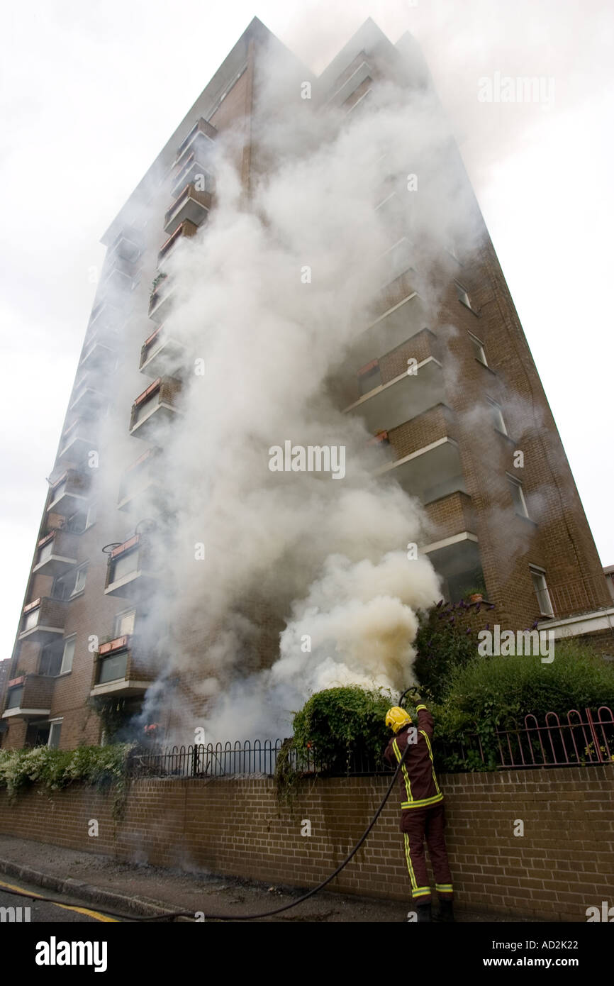 Fireman estinzione di incendi nel giardino sul retro di un appartamento al primo piano a sud di Londra Foto Stock