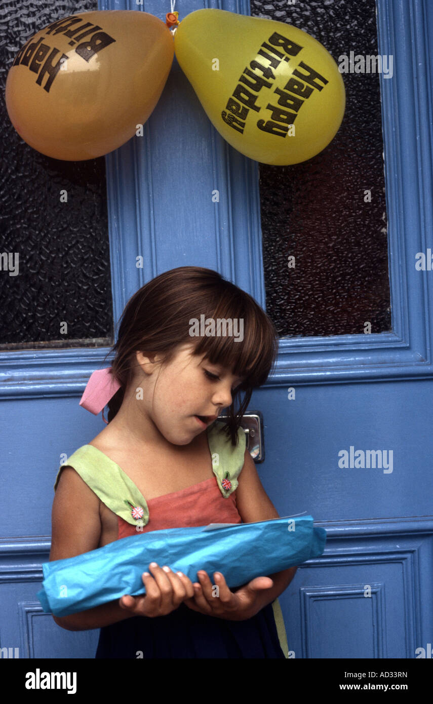 6 anno vecchia ragazza tenendo un presente in attesa presso lo sportello anteriore pronto per immettere la festa di compleanno Foto Stock