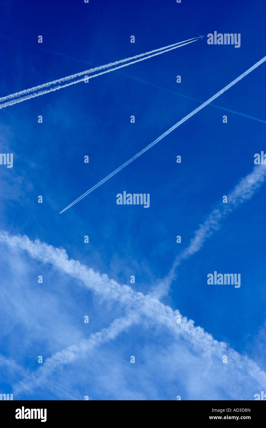 Velivoli a getto di vapore di scarico percorsi che attraversano il cielo blu Foto Stock