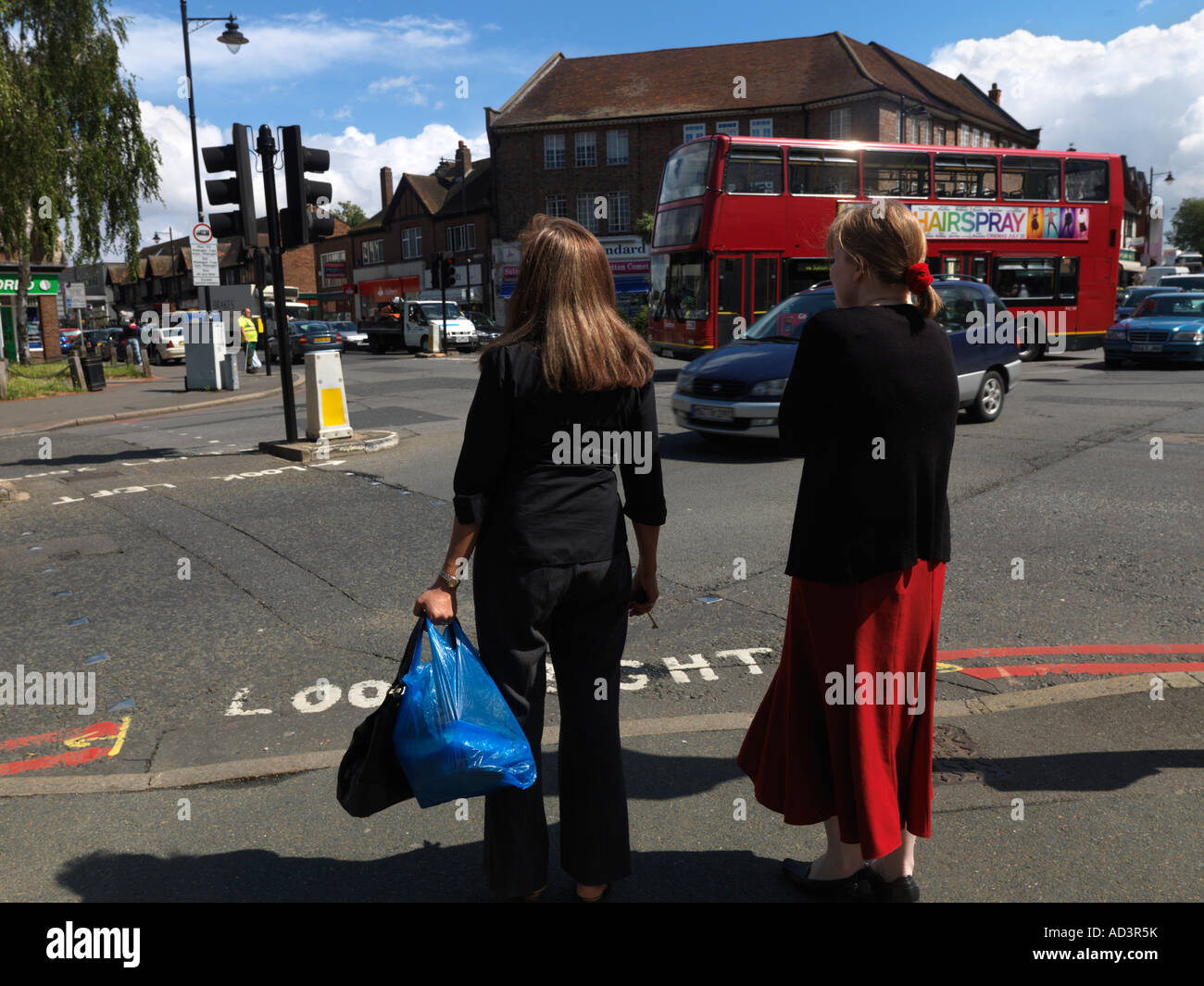 Cheam Surrey in Inghilterra due adolescenti attraversando il bivio al passaggio pedonale al semaforo Foto Stock