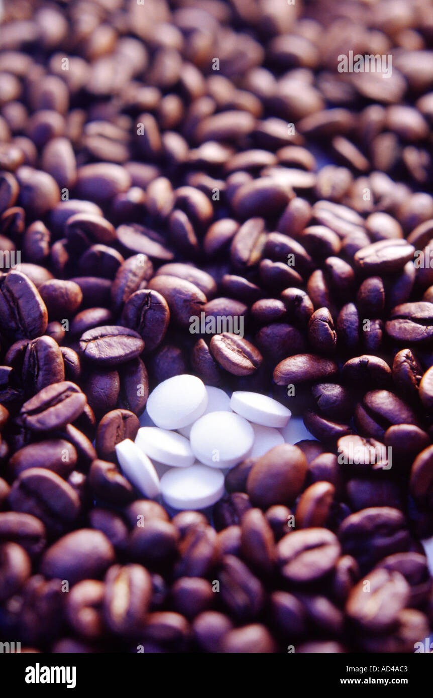 I chicchi di caffè con alcune compresse bianche nella parte inferiore del telaio di un concetto o di sfondo Foto Stock