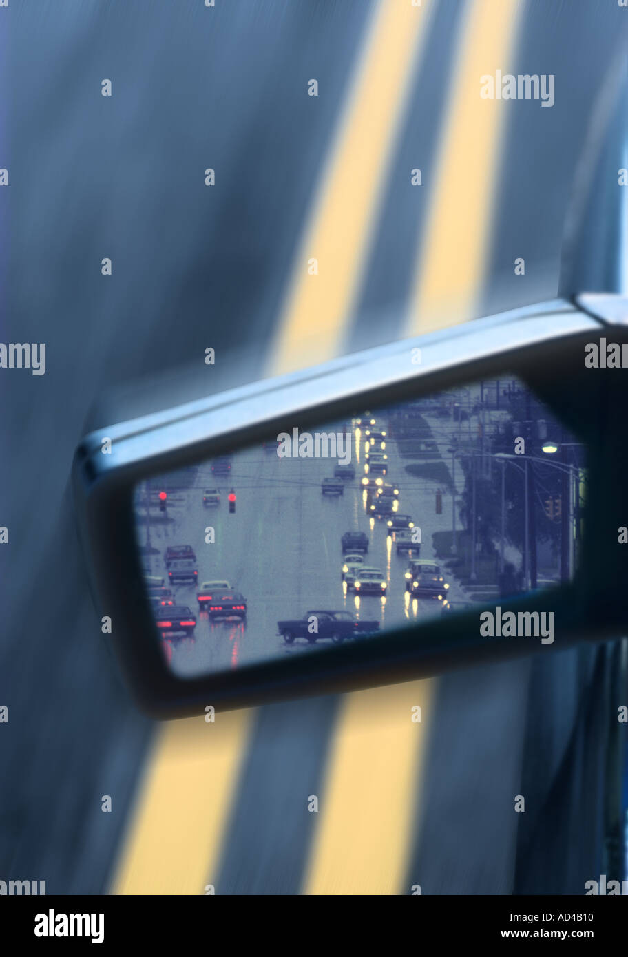 Primo piano del lato auto specchio riflettendo piovosa scena di traffico Foto Stock