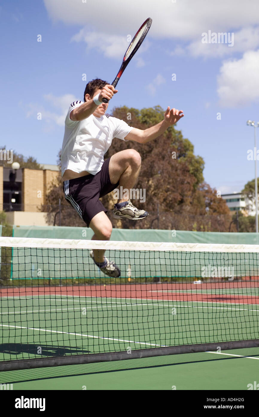 Un giocatore di tennis saltando su di un campo da tennis net Foto Stock