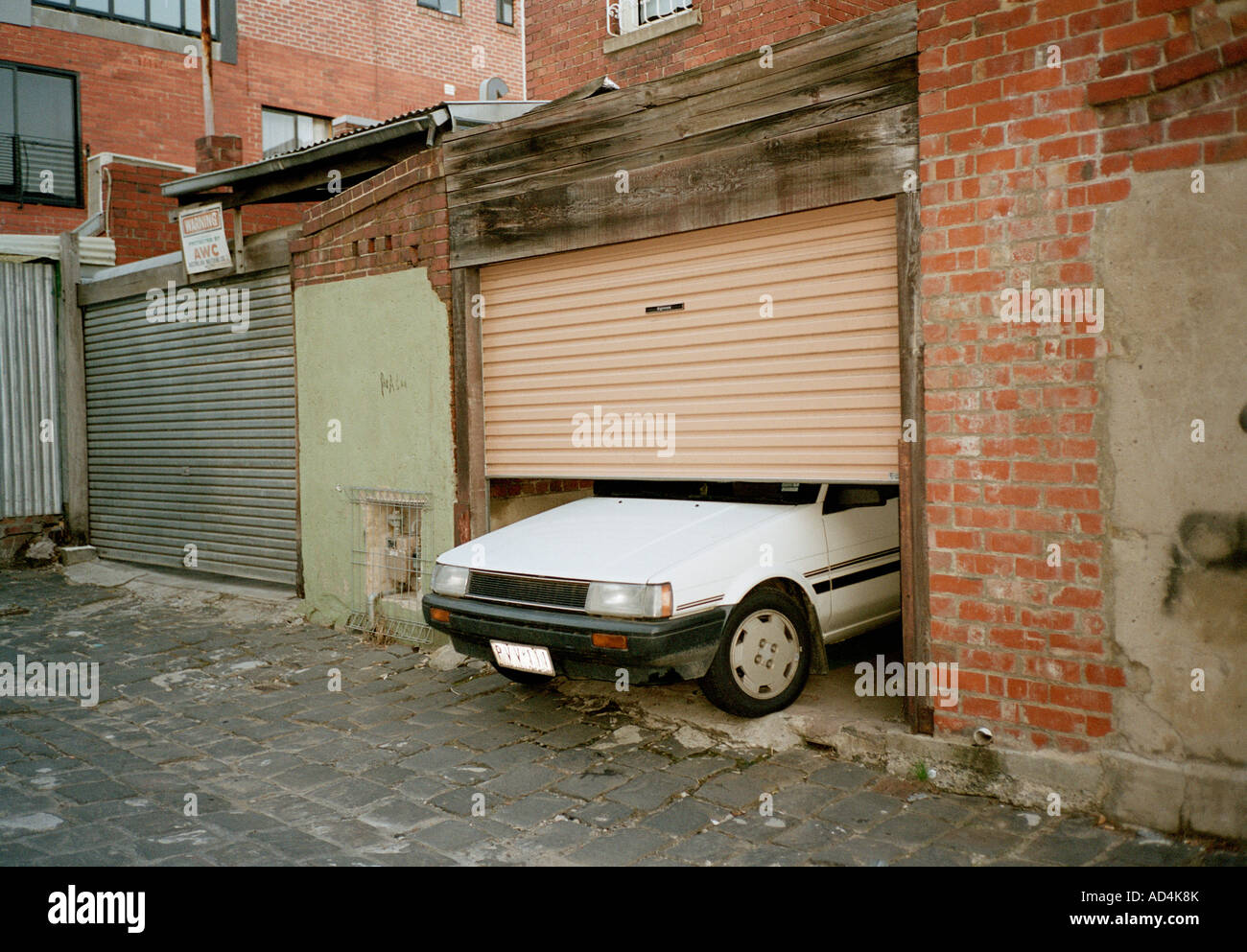 Una vettura inserimenti attraverso una porta di garage Foto Stock