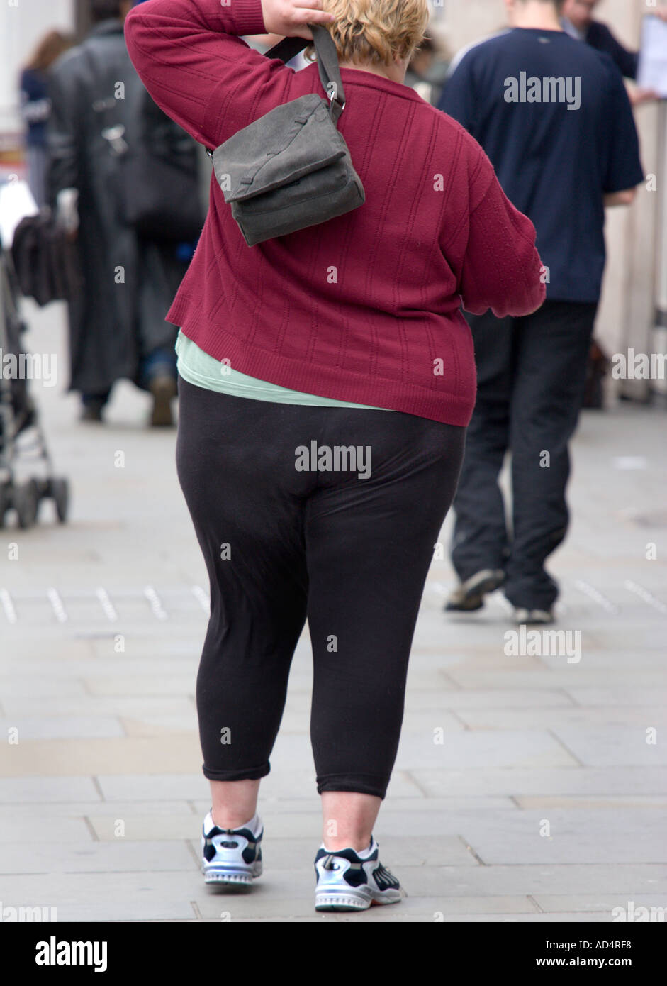 Vista posteriore di una donna obesa camminare portando un sacchetto Foto Stock
