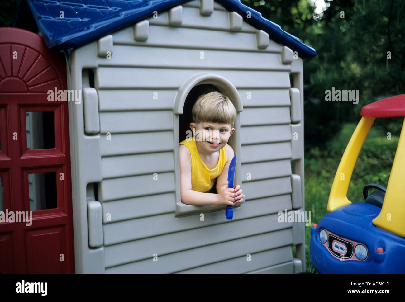 Piccolo ragazzo in una playhouse a guardare fuori dalla finestra Foto Stock