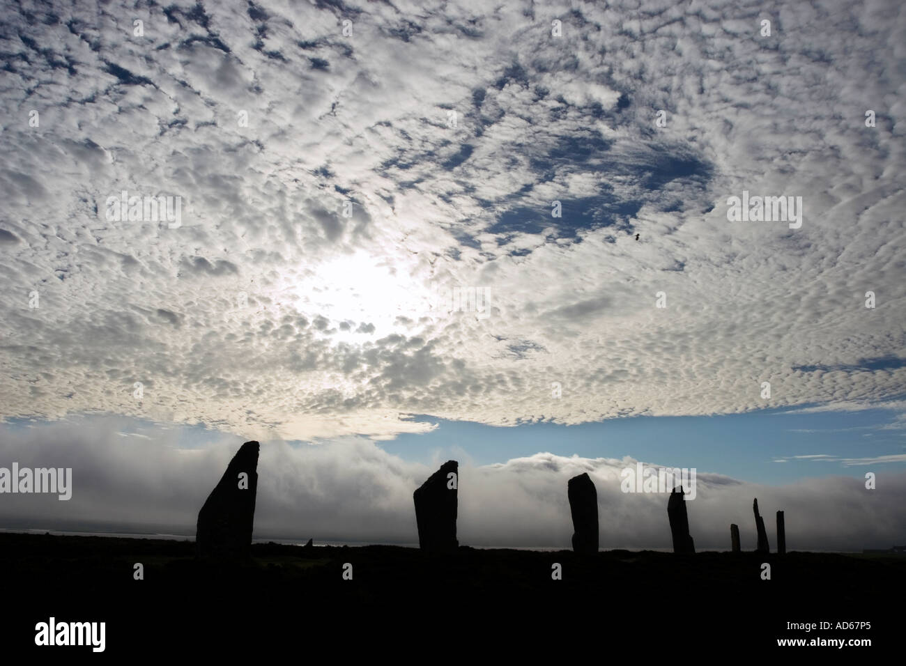 Anello di Brogar pietre permanente silhouette a sunrise contro un cielo nuvoloso scuro sulle isole di Orkney, isole settentrionali della Scozia Foto Stock