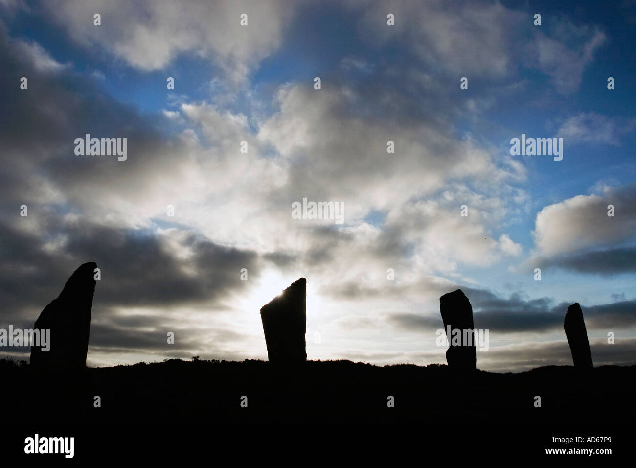 Anello di Brogar pietre permanente silhouette a sunrise contro un cielo nuvoloso scuro sulle isole di Orkney, isole settentrionali della Scozia Foto Stock