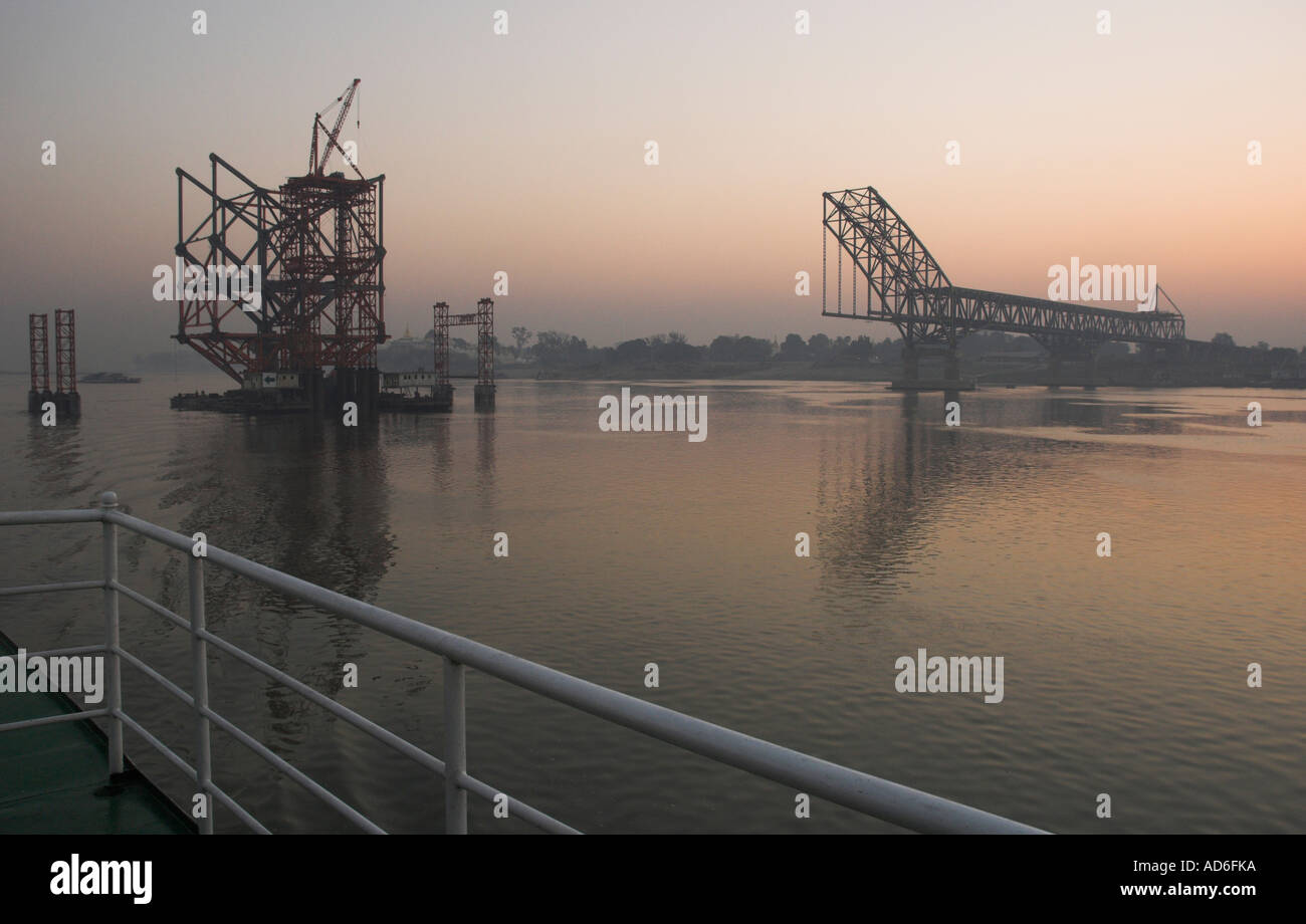Myanmar Birmania Ayeryarwady fiume vicino a Mandalay ponte sito in costruzione vista al tramonto visto da una barca Foto Stock