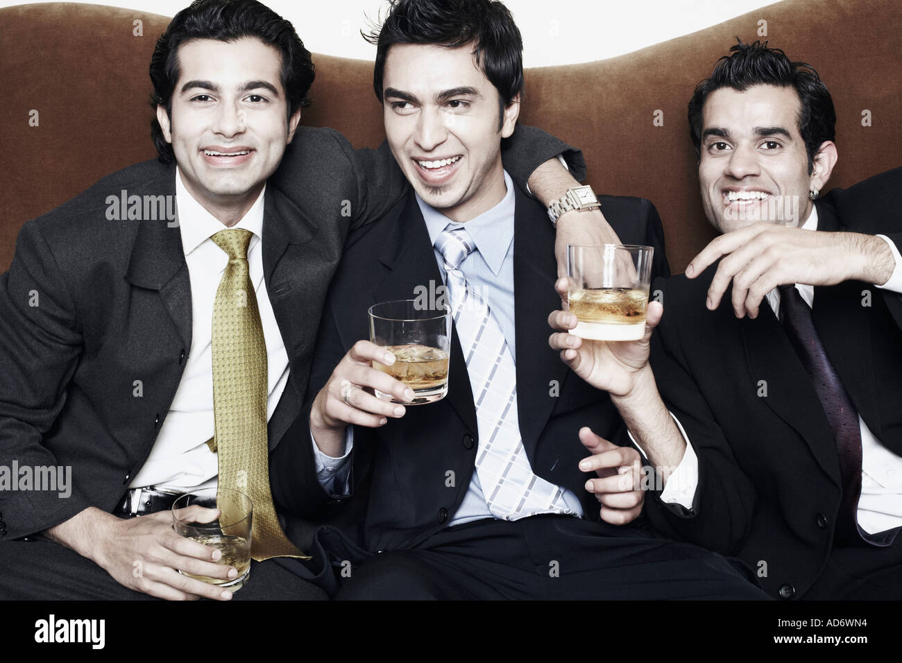 Close-up di tre giovani uomini che tengono i bicchieri di whiskey Foto Stock