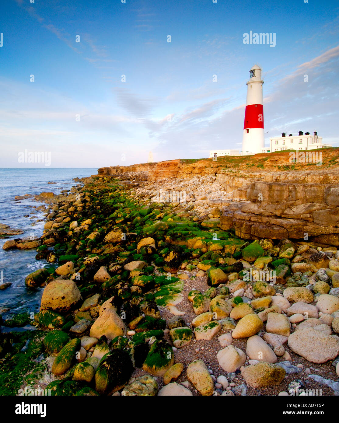 Portland bill lighthouse all'alba presi da una scogliera sopra il promontorio insidiose rocce sulla foreshore al di sotto di Foto Stock