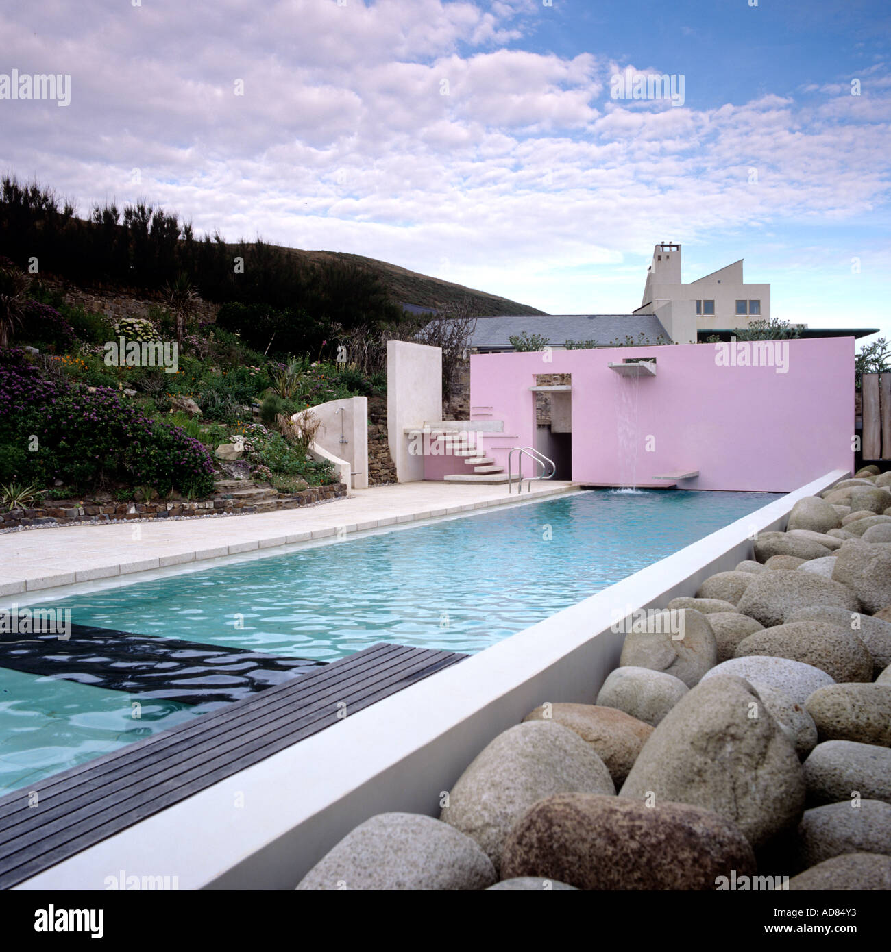 Piscina esterna con pietra paesaggio e design esterno del moderno edificio rosa Foto Stock