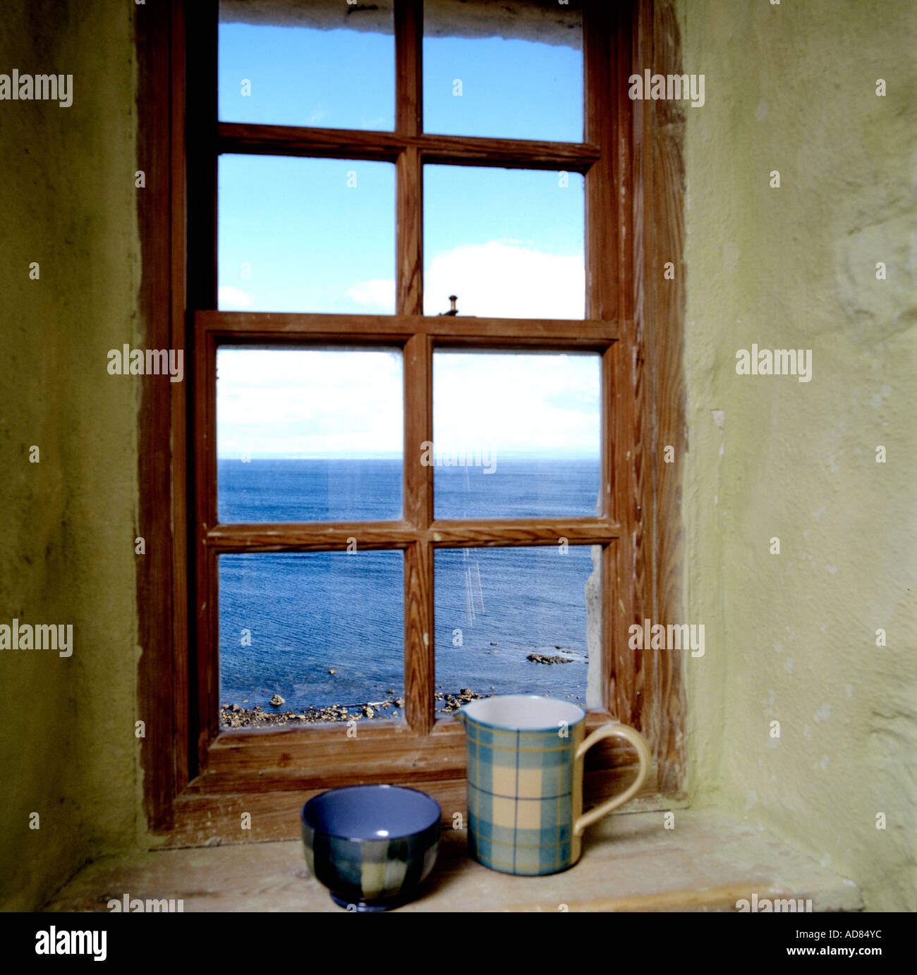 Boccale di tartan e ciotola sul davanzale di una finestra con una vista sul mare in un castello scozzese. Foto Stock