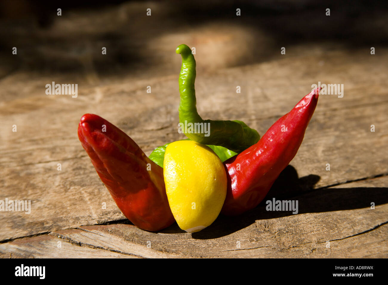 Grani di pepe rosso pepe verde e un quarto di un limone sul tavolo di legno Foto Stock