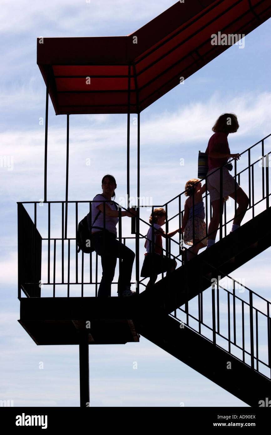 Due madri e i loro figli salire una rampa di scale esterne. Foto Stock
