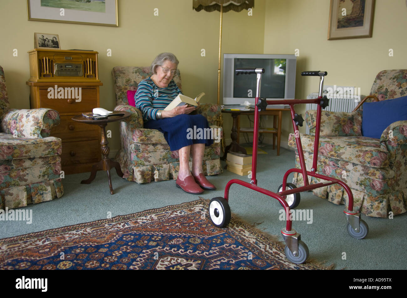 Anziana vedova con telaio a piedi la lettura nella sua unità di pensionamento Foto Stock