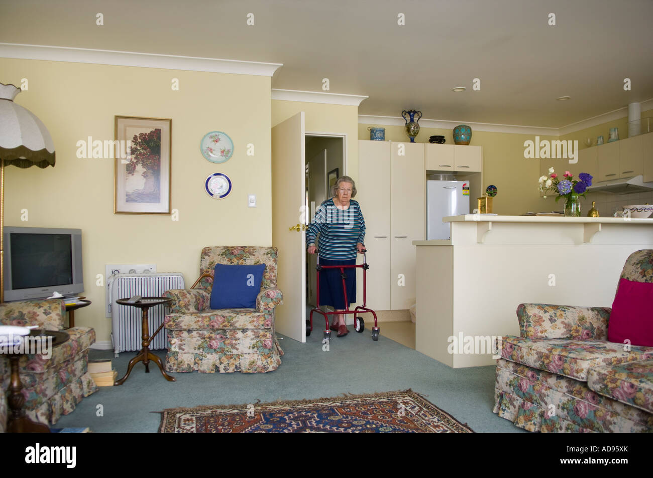 Anziana vedova con telaio a piedi nella sua unità di pensionamento Foto Stock