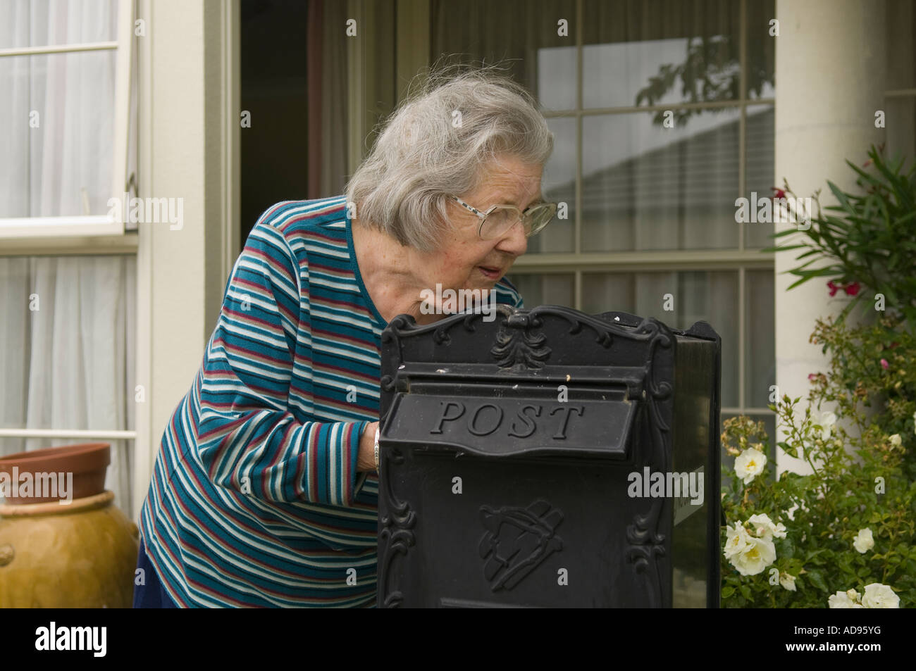 Signora anziana cancella la sua buca delle lettere Foto Stock