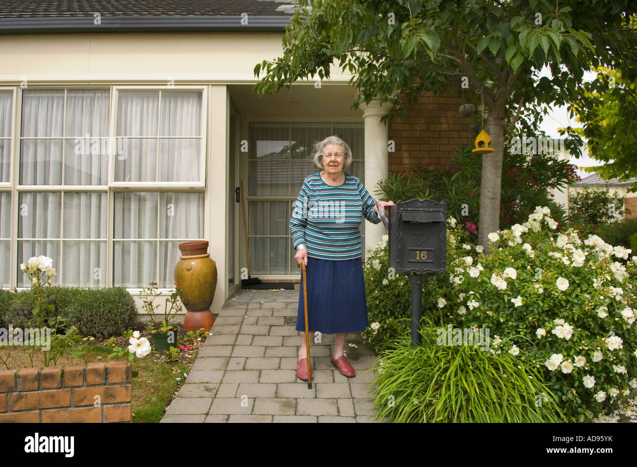 Signora anziana nel giardino della sua unità di pensionamento a Christchurch Nuova Zelanda Foto Stock