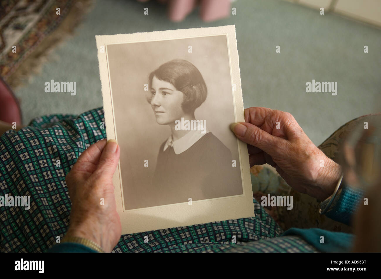 Anziana vedova detiene una fotografia di se stessa come una giovane donna Foto Stock