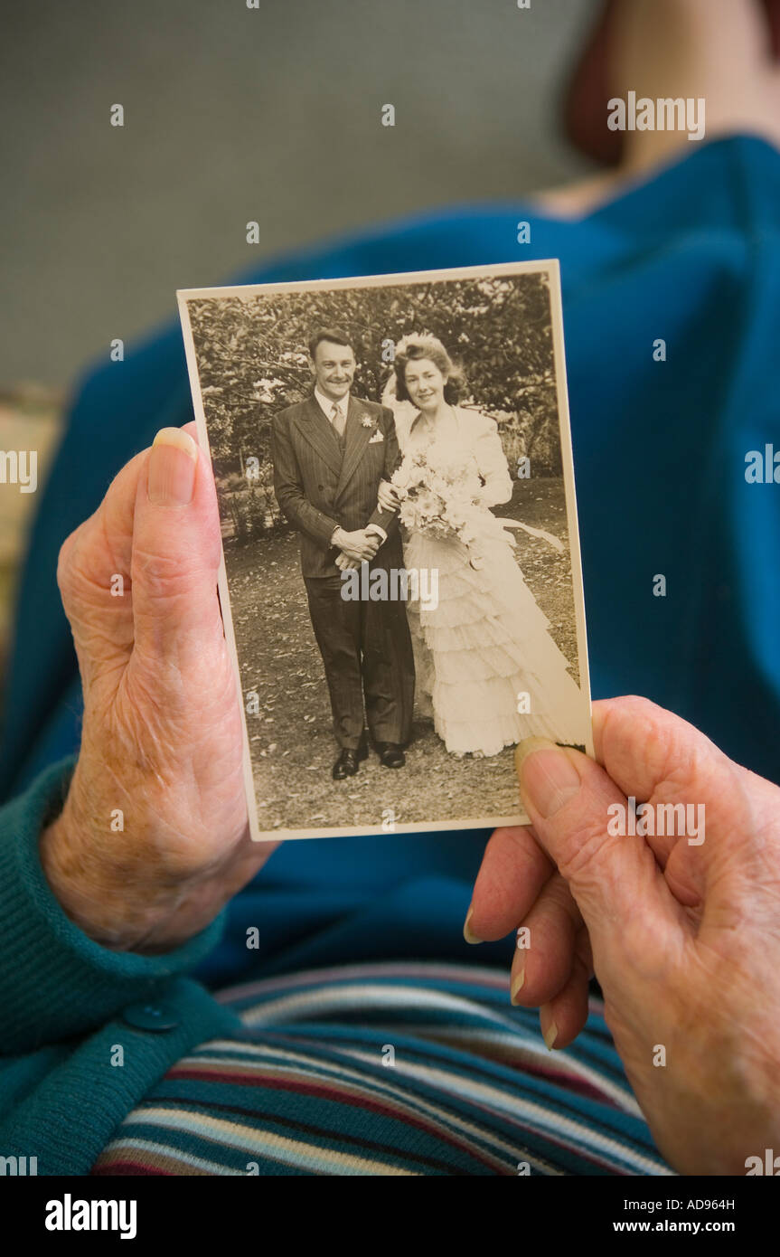 Anziana vedova guarda alla fotografia di se stessa e il marito il giorno delle nozze Foto Stock