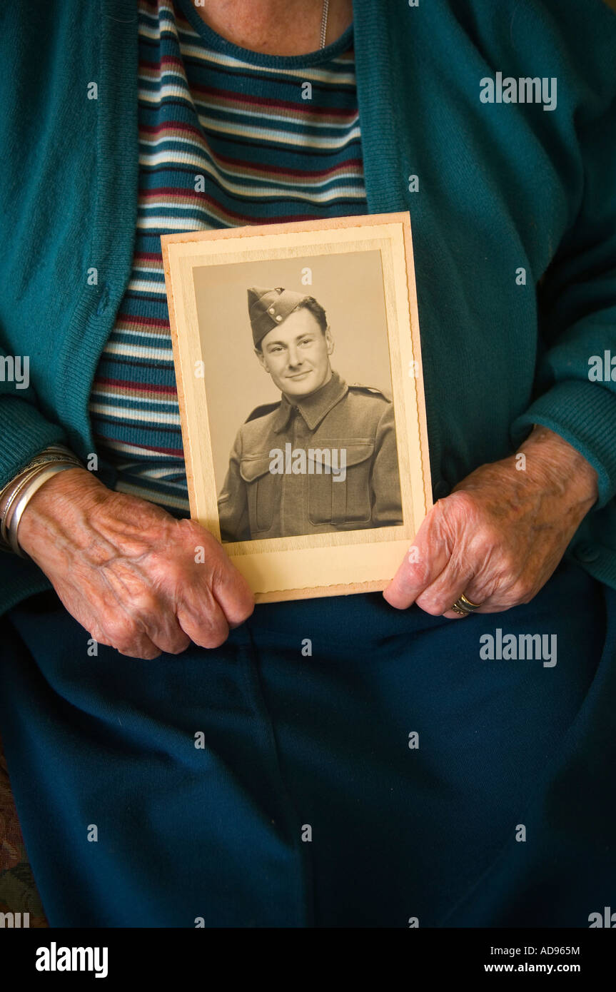 Signora anziana detiene una foto del marito come un giovane soldato Foto Stock