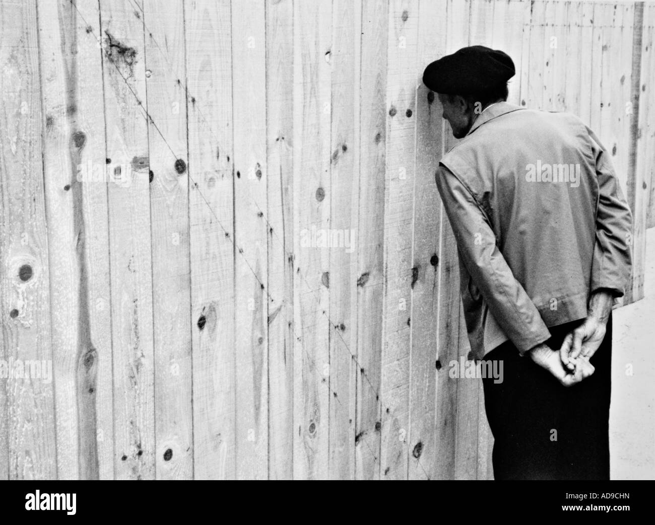 No signor street photography curioso uomo facendo leva tramite una recinzione di legno Foto Stock