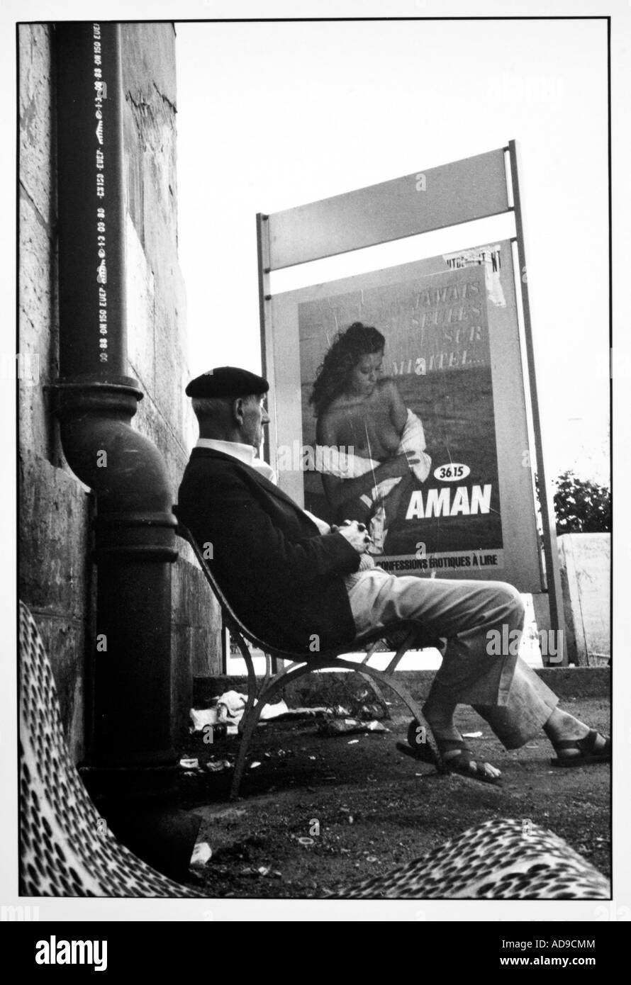 No signor street photography vecchio seduto su una panchina di fronte ad un poster pubblicitario con una giovane donna bellissima Foto stock - Alamy