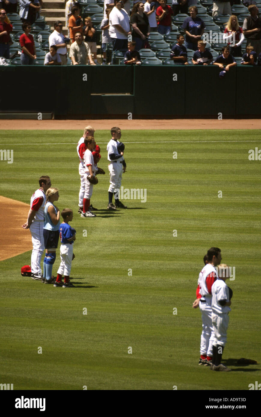 I giocatori di baseball e membri della famiglia in pausa per una riproduzione su l'inno nazionale prima di una partita al campo di Edison in Califor Anaheim Foto Stock