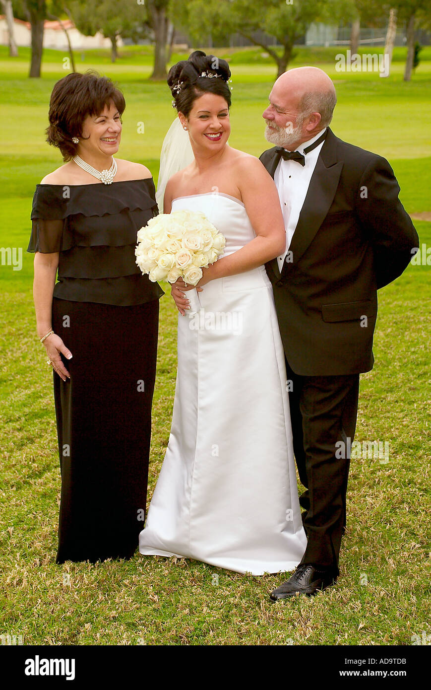 Il giorno del matrimonio una sposa pone con i suoi genitori prima di lasciare per un formale le nozze cattoliche in Irvine California Foto Stock