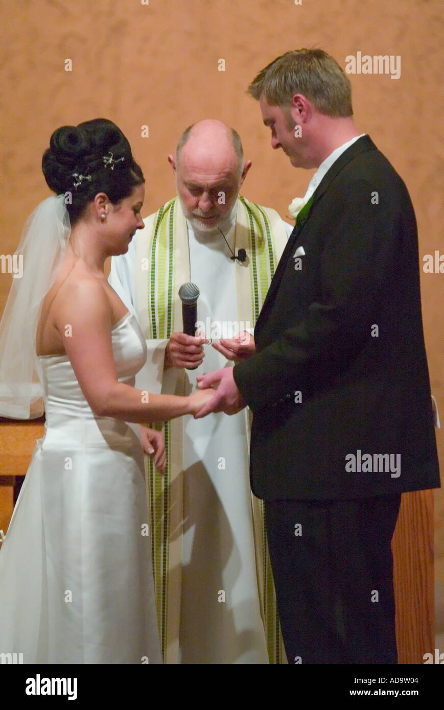 Il sacerdote pone l'anello sullo sposo s dito formale a nozze cattoliche in Irvine California Foto Stock