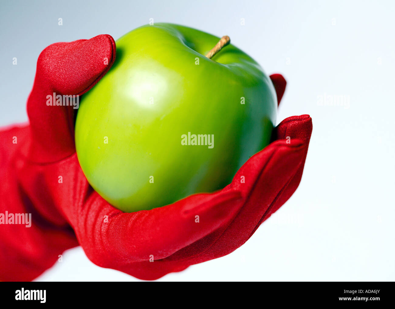 Green appel tenuto in mano con red glove Foto Stock