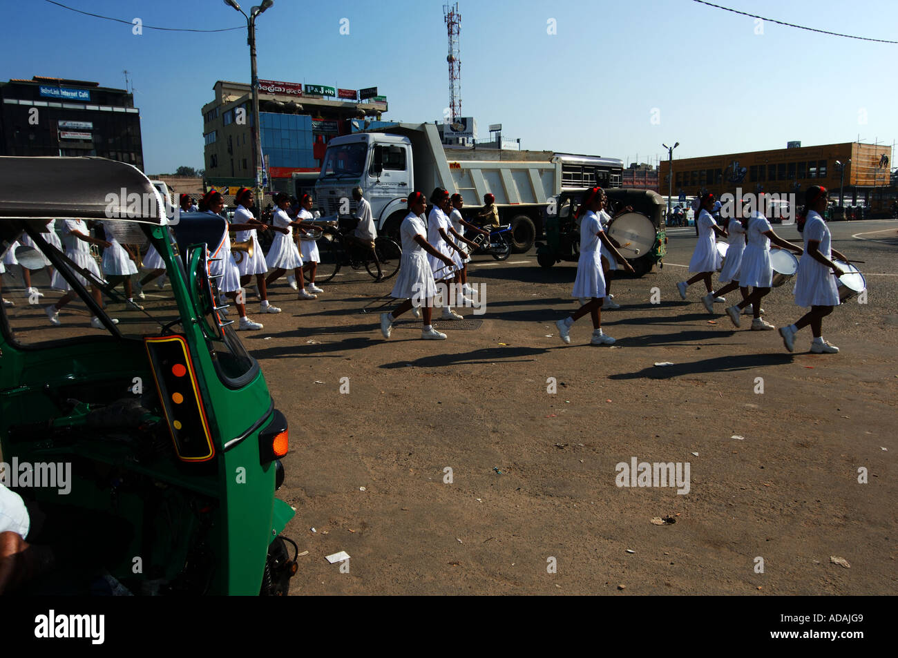 Galle della banda musicale della scuola ragazze marciando attraverso il traffico Foto Stock