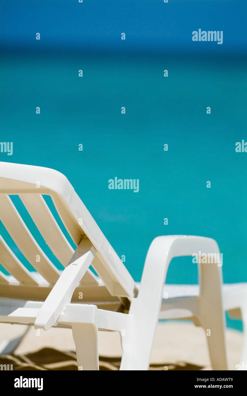 Bianco vuoto sedia a sdraio su una spiaggia tropicale con blu brillante di acque di mare Foto Stock
