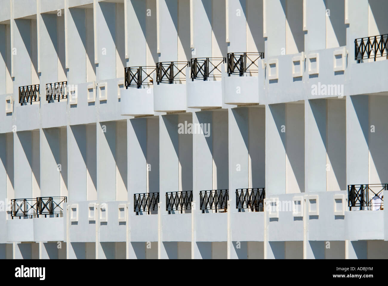 Abstract orizzontale close up di nero di balconi in ferro battuto sulla facciata anteriore di un bianco hotel al sole. Foto Stock