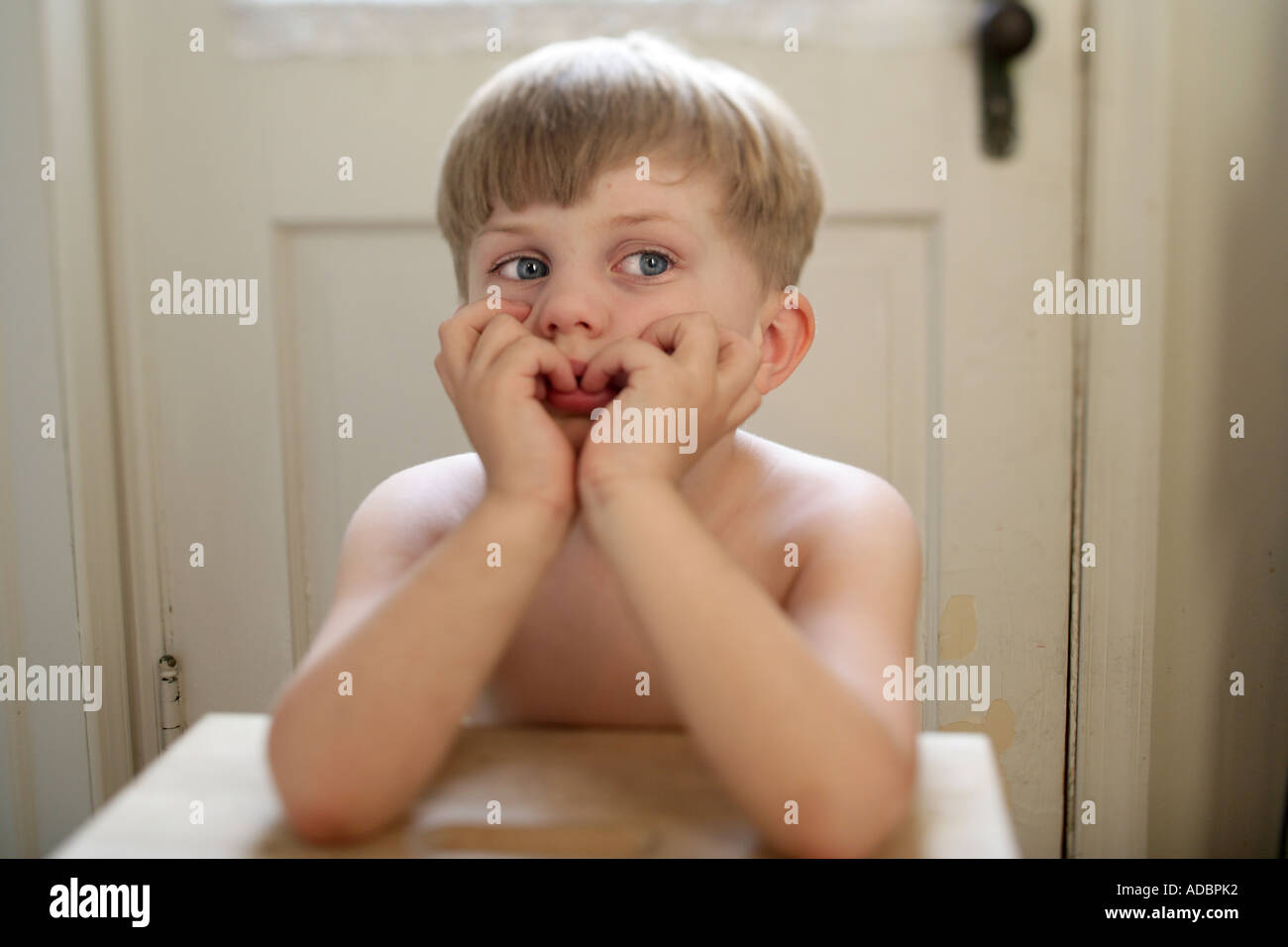 Un annoiato bambino seduto al tavolino cercando infelice e premuto Foto Stock