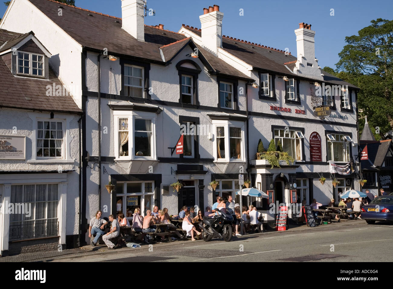 Persone di bere al di fuori di una casa pubblica sul marciapiede in estate il Galles Llangollen Regno Unito Foto Stock