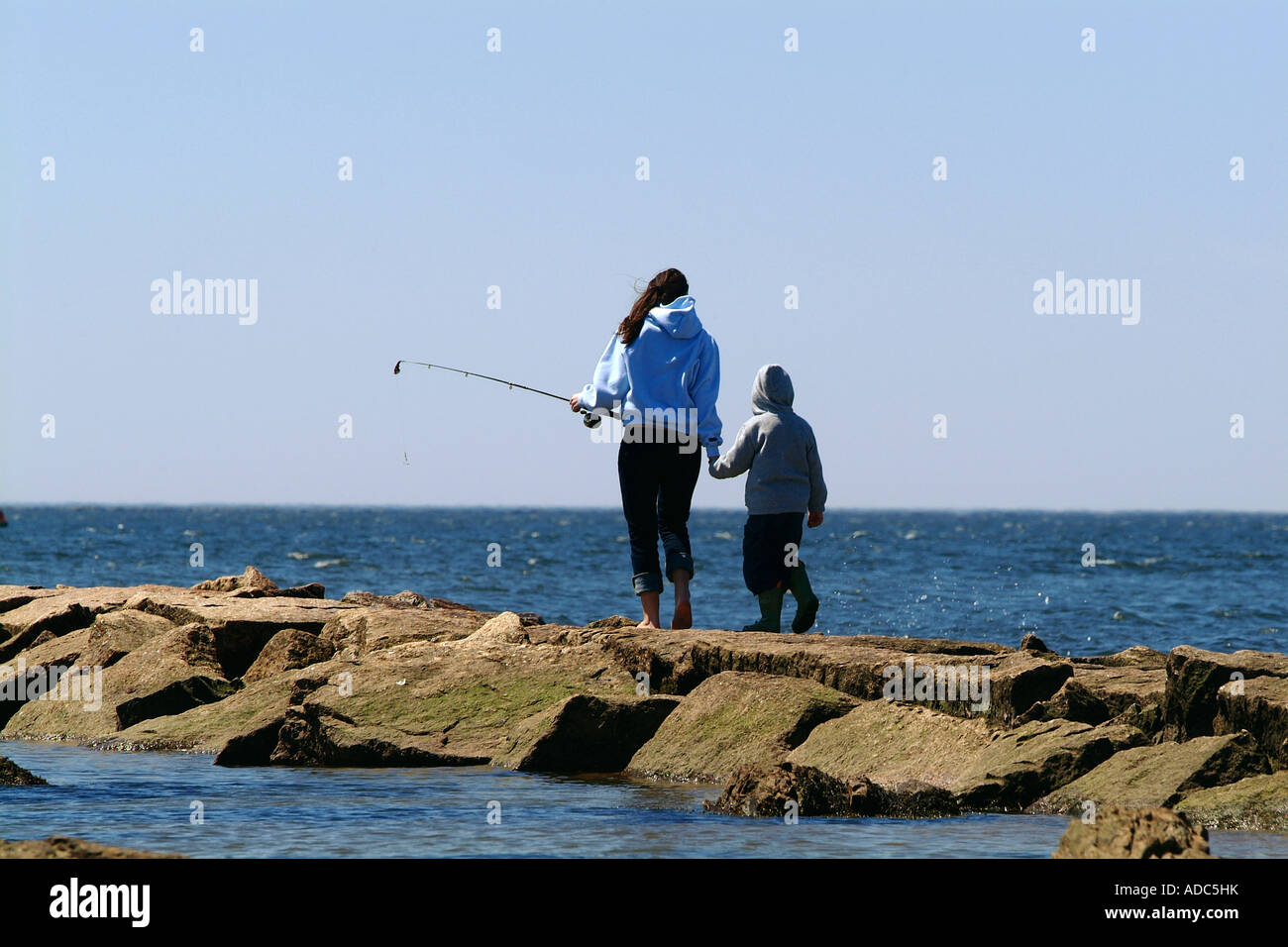Una giovane madre con bambino cammina lungo un pontile per andare a pesca Foto Stock
