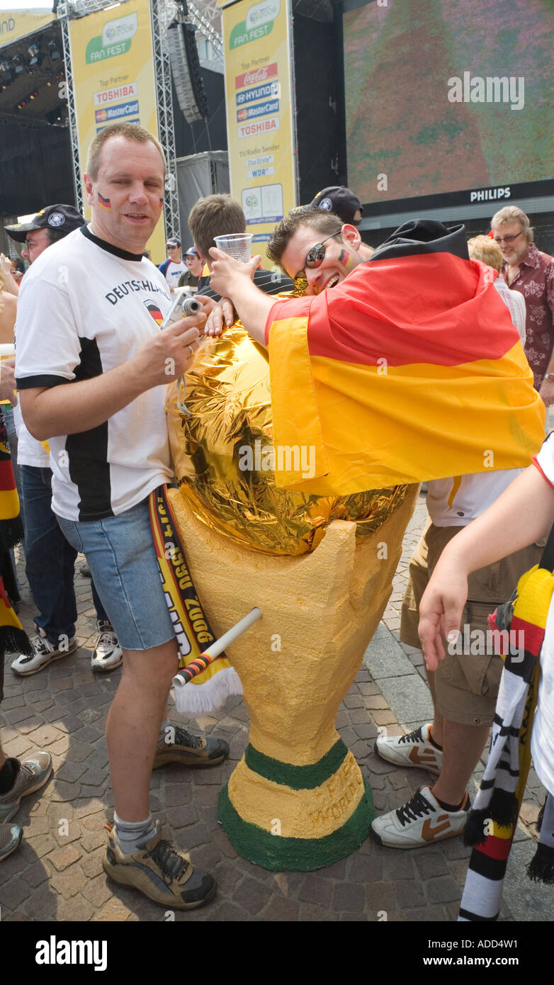 Tifosi tedeschi godendo i giochi di calcio con una grande riproduzione della Coppa del Mondo FIFA presso un pubblico visualizzazione Evento Foto Stock