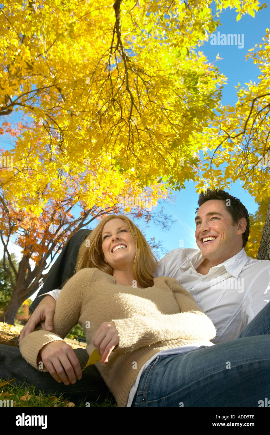 30's Caucasian giovane siede sotto Golden Autumn alberi Foto Stock