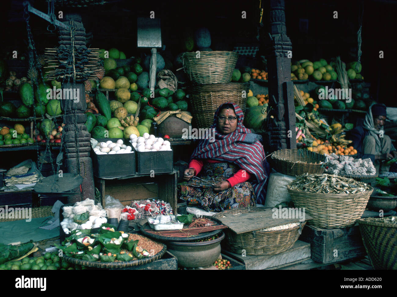 Donna stallholder holding coltello per tagliare la frutta a vendere nel mercato a Kathmandu in Nepal Foto Stock