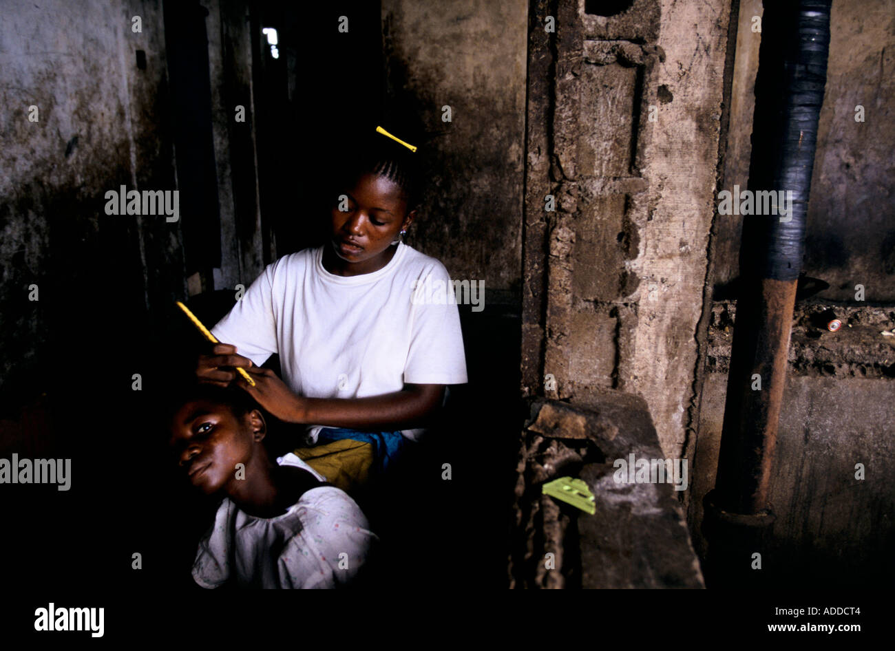 Charles Taylor s Liberia può 96 ragazza ha i suoi capelli intrecciati a sfollati centro in edificio abbandonato a Monrovia Foto Stock