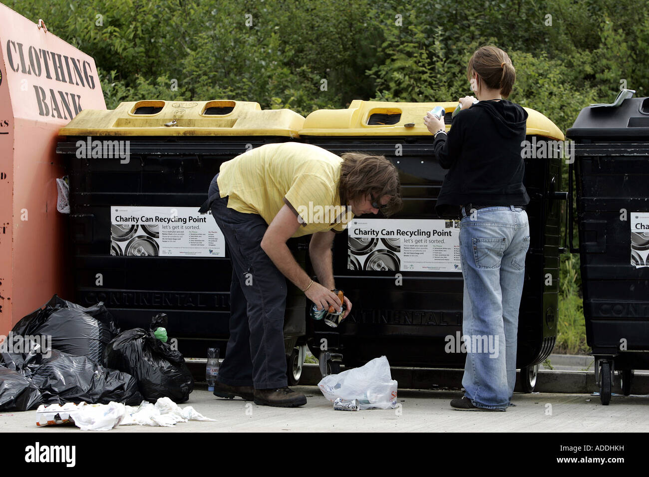 Una giovane coppia il riciclo dei barattoli di alluminio in un supermercato area di riciclaggio. Foto Stock