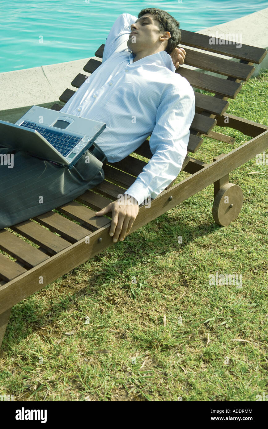 Imprenditore sdraiata su una lounge chair, laptop in giro a occhi chiusi Foto Stock