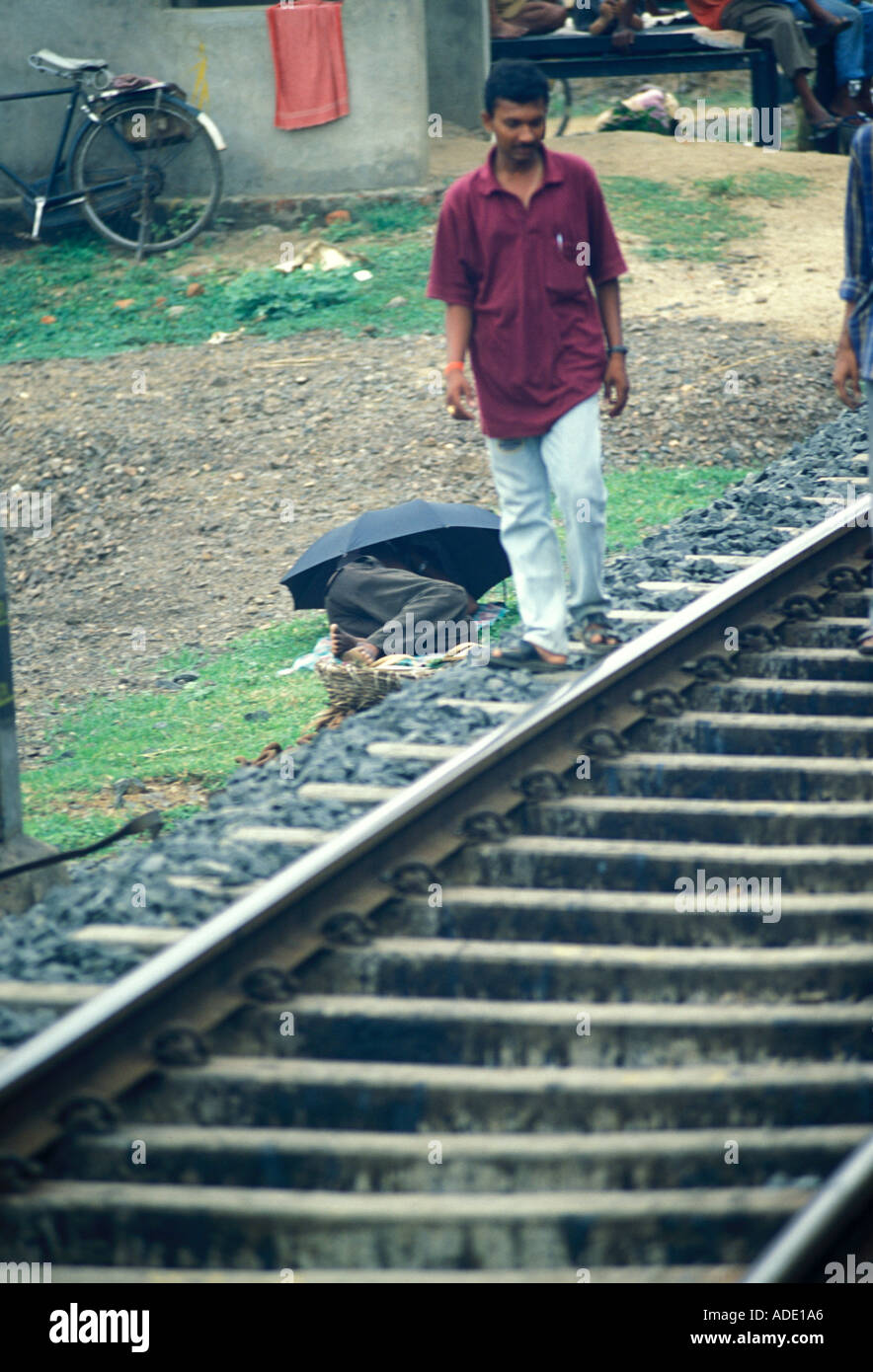 East Indian uomo cammina da persona che giace accanto al binario ferroviario in India nelle zone rurali fermata Foto Stock