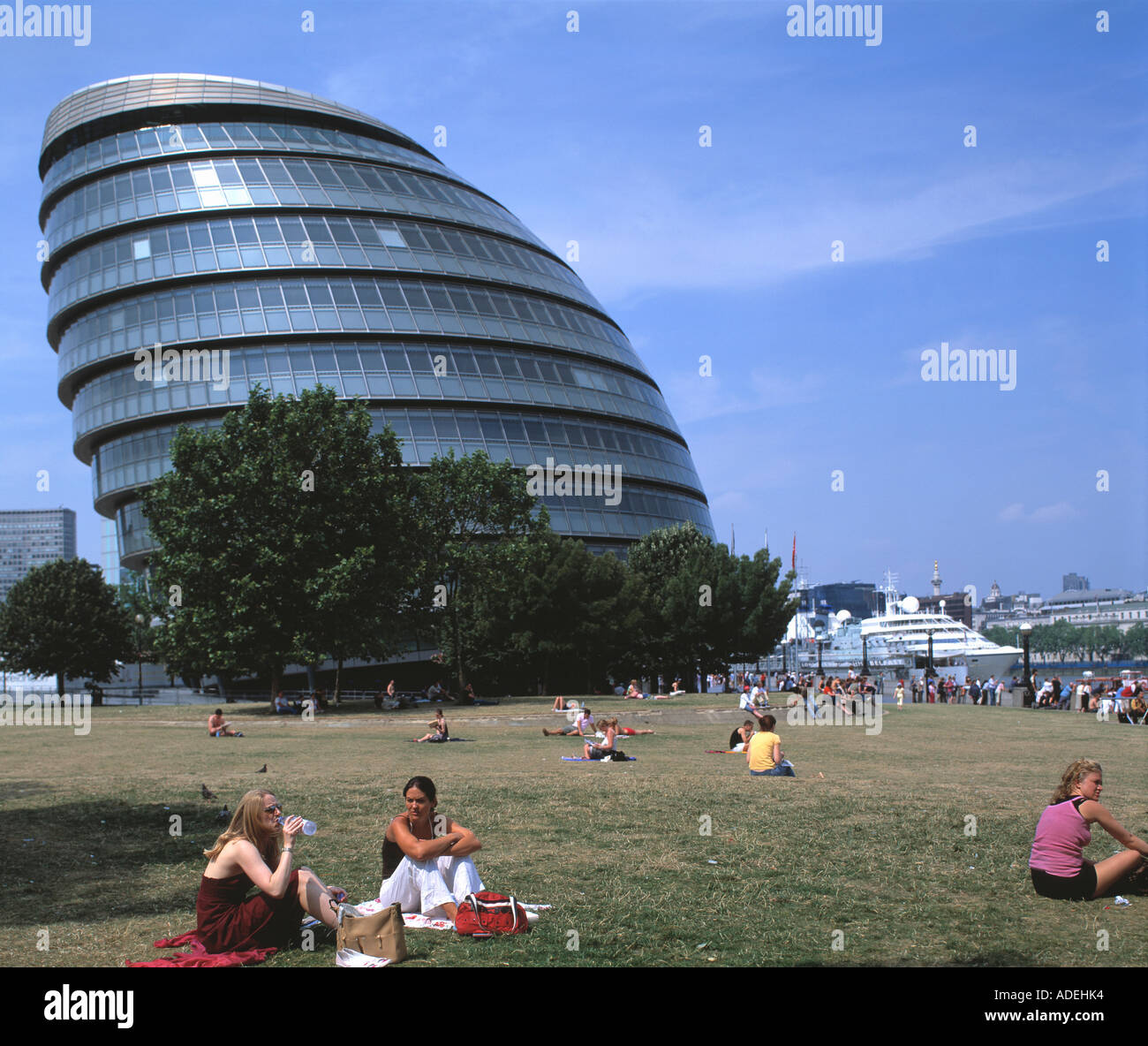 Regno Unito. In Inghilterra. Londra. Vista del nuovo municipio edificio e la gente seduta sul prato del parco circostante. Foto Stock